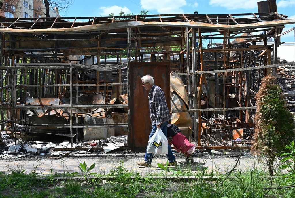 Seorang pria berjalan melewati sebuah bangunan toko yang rusak akibat perang di Kharkiv, Selasa (7/6/2022). 