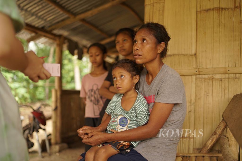 Yuliana Konda (35) mendengarkan penjelasan petugas puskesmas terkait gizi anak saat berkunjung ke rumahnya pada Kamis (10/11/2022) sembari memangku anak bungsunya, Aderensi (4), di Sumba Barat Daya, NTT.