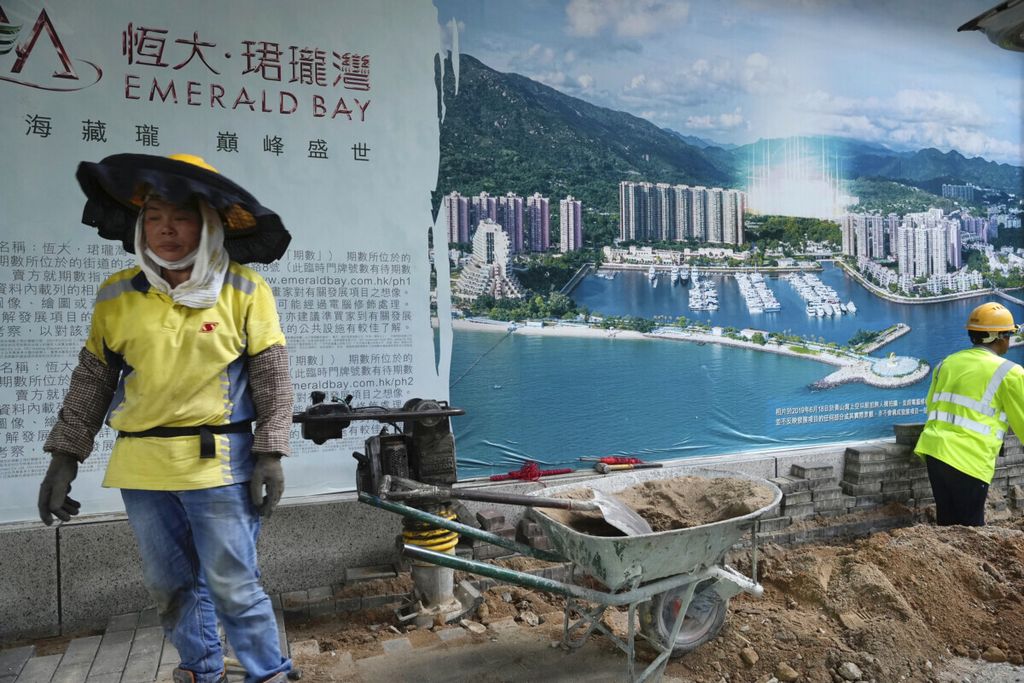 Seorang pekerja berjalan di depan iklan properti Evergrande di Hong Kong, 4 Oktober 2021. 