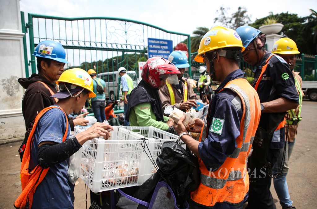 Pekerja proyek MRT fase II berbelanja makan siang dari pedagang keliling di sekitar Monas, Jakarta Pusat, Selasa (23/01/2024). Proyek infrastruktur dan properti di Jakarta dan sekitarnya menyerap banyak tenaga kerja di sektor informal.  