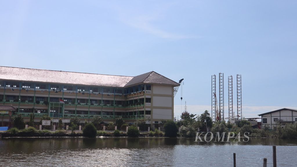 Tiang-tiang pendukung aktivitas bongkar muat di sebuah pelabuhan terlihat di samping sekolah satu atap yang terdiri dari SDN 05, SMPN 290 dan SLB Negeri 08, di Marunda, Cilincing, Jakarta Utara. Pelabuhan itu kerap menerima muatan abu batubara yang mengotori lingkungan sekolah dan pemukiman sekitarnya.