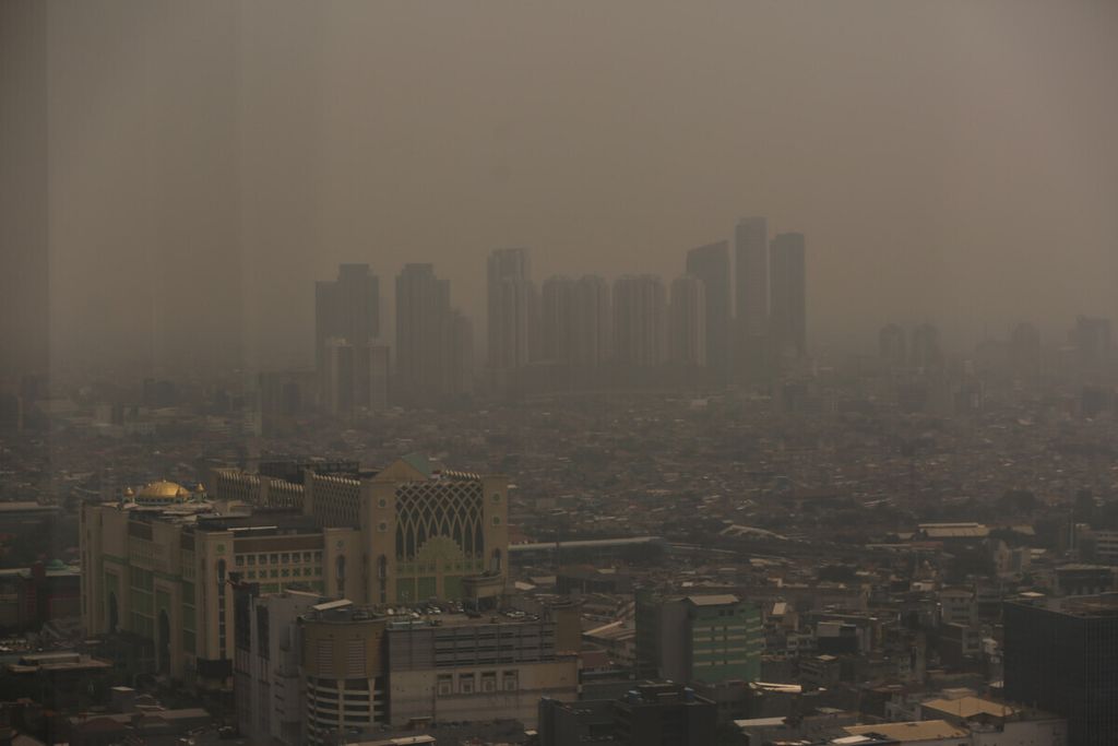 Lanskap Kota Jakarta yang diselimuti asap polusi udara, Rabu (24/7/2019) pada pukul 12.00. Sampai saat ini, meskipun ada pembatasan kegiatan masyarakat selama pandemi Covid-19, polusi udara masih terjadi karena masih banyaknya aktivitas tidak ramah lingkungan di Jakarta ataupun kawasan sekitarnya.