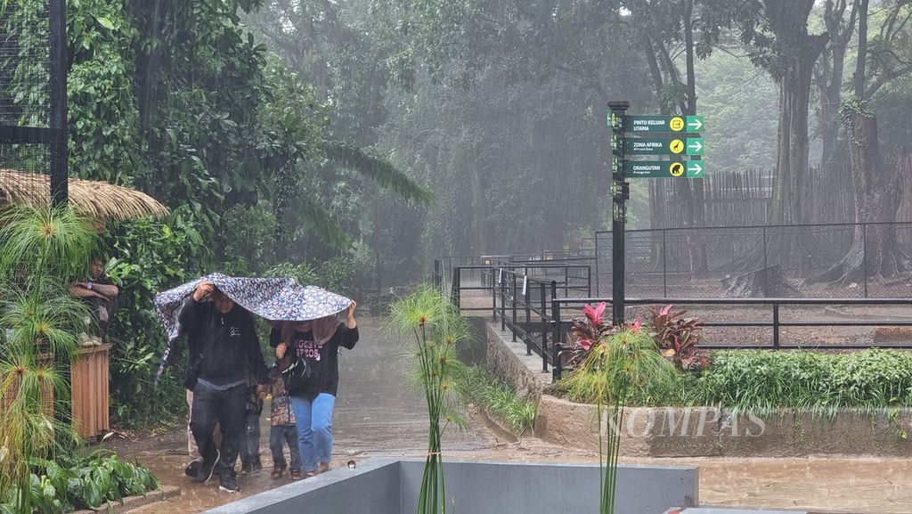 Sejumlah pengunjung menggunakan terpal untuk melindungi diri dari hujan saat mengunjungi Kebun Binatang Bandung, Jawa Barat, Senin (24/4/2023).