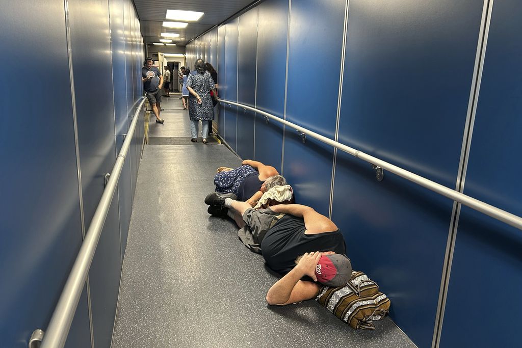 Penumpang di Bandara Internasional Los Angeles tidur di selasar untuk penerbangan United Airlines yang tertunda ke Bandara Internasional Dulles karena pemadaman listrik global yang meluas, Jumat (19/7/2024).