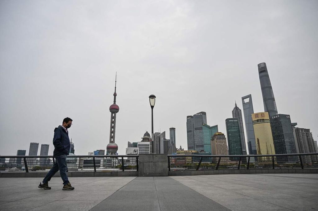 Seorang pria berjalan di area pejalan kaki di pinggir Sungai Huangpu dengan pemandangan latar belakang gedung-gedung tinggi di Distrik Pudong yang ditutup secara total (<i>lockdown</i>) guna mengendalikan penularan wabah Covid-19 di Shanghai, China, Senin (28/3/2022).