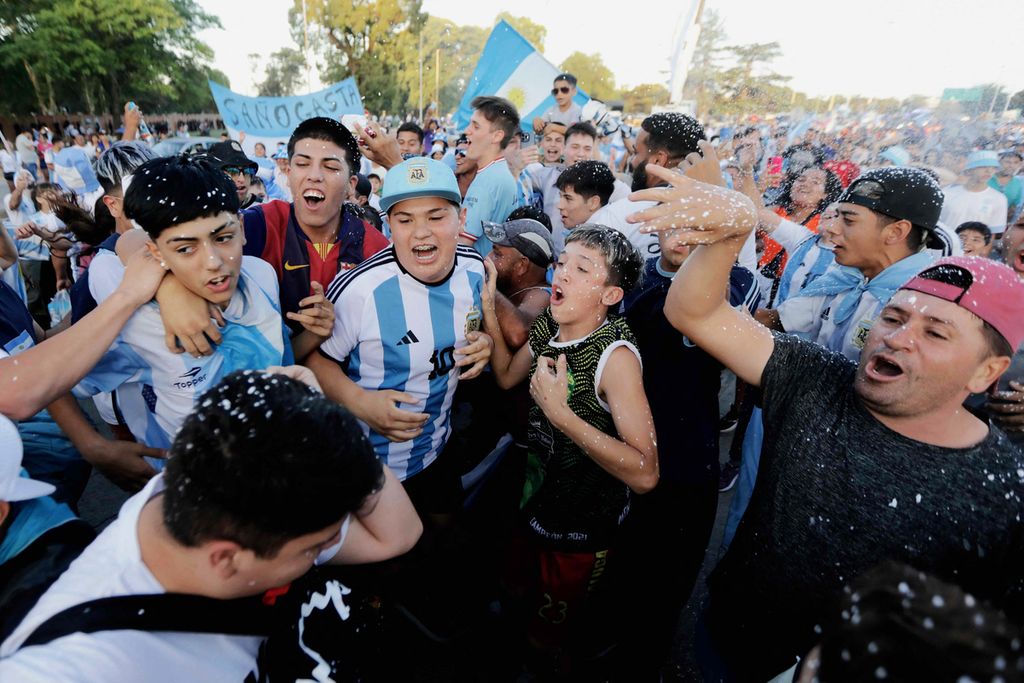 Fans of Argentina cheer while waiting for the arrival of the team after winning the Qatar 2022 Fifa World Cup final football match against France, in Ezeiza, Buenos Aires province, Argentina, on December 19, 2022. - Football star Lionel Messi and his teammates will be received as heroes in Buenos Aires, where millions of excited people await their arrival to celebrate together the World Cup obtained, the third that the Albiceleste has added in its history. 