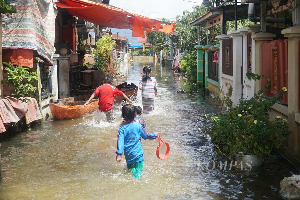 Anak-anak berjalan di jalan perumahan yang terendam banjir di Desa Koto Dian, Kecamatan Keliling Danau, Kabupaten Kerinci, Jambi, Kamis (18/1/2024). Banjir yang merendam permukiman di sekitar Danau Kerinci ini mulai surut. Banjir dan longsor melanda 16 kecamatan dan 95 desa di kabupaten ini sejak awal tahun 2024 dengan jumlah warga terdampak hingga 16 Januari sebanyak 6.668 keluarga dan 19.634 jiwa. 