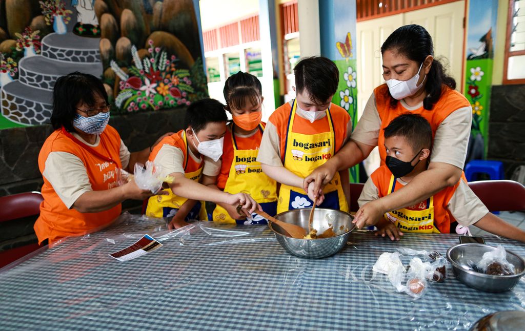 Siswa <i>down syndrome</i> bersama guru pendamping bekerja sama mencampur adonan saat mengikuti pelatihan membuat kue kering Puppy Cookies di Sekolah Kebutuhan Khusus Sang Timur, Karang Tengah, Kota Tangerang, Banten, Senin (21/3/2022).