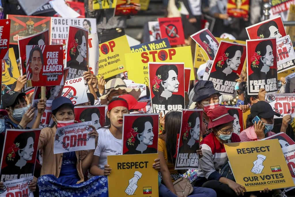 Demonstran membawa poster pemimpin Myanmar yang ditahan Aung San Suu Kyi dan poster bertuliskan untuk menghormati hasil pemilu dalam aksi menentang kudeta militer di Yangon, Myanmar Selasa (16/2/2021). 