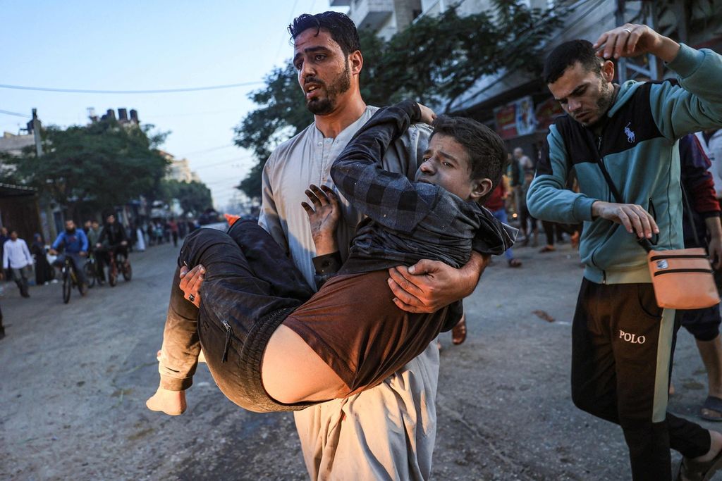 Seorang pria Palestina menggendong seorang anak yang terluka akibat serangan Israel di Rafah, wilayah selatan Jalur Gaza, Minggu (3/12/2023). 