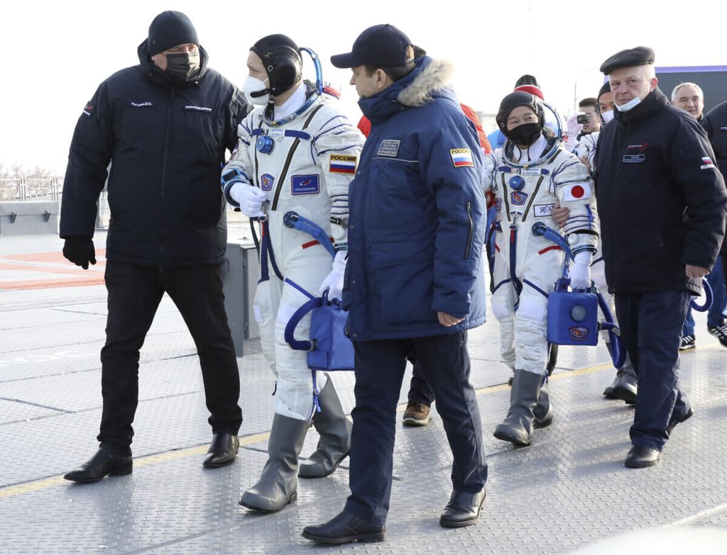 Kosmonot Rusia Alexander Misurkin (kedua dari kiri) diikuti di belakangnya, miliarder Jepang Yusaku Maezawa (dalam baju kosmonot) dan asistennya Yozo Hirano ditemani kru Roscosmos berjalan menuju roket dan wahana antariksa yang akan membawanya ke Stasiun Luar Angkasa Internasional di kosmodrom Baikonur, Kazakhstan, Rabu (8/12/2021).