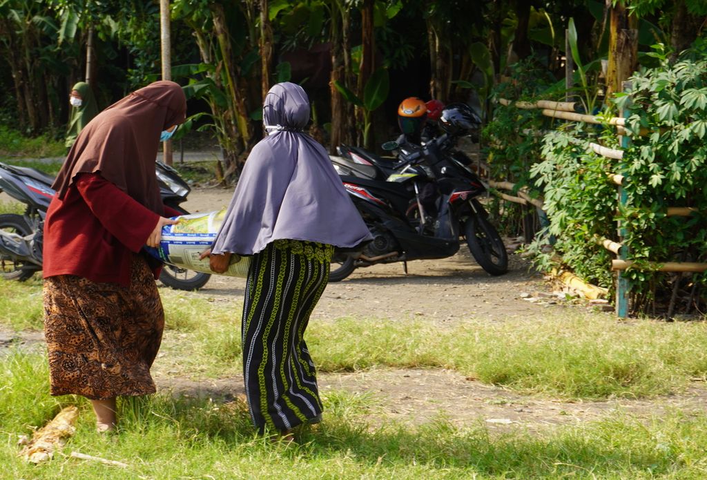 Warga menggotong beras bantuan dari pemerintah di Kelurahan Panggung, Kota Tegal, Jawa Tengah, Jumat (27/8/2021).