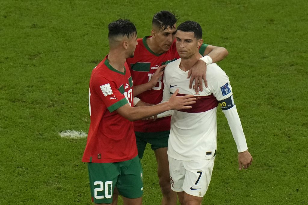Dua pemain Maroko, Achraf Dari (kiri) dan Jawad El Yamiq, berusaha menghibur kapten Portugal, Cristiano Ronaldo, seusai Maroko mengalahkan Portugal di laga 16 Besar Piala Dunia Qatar 2022 di Stadion Al Thumama, Doha, Qatar, 10 Desember 2022.