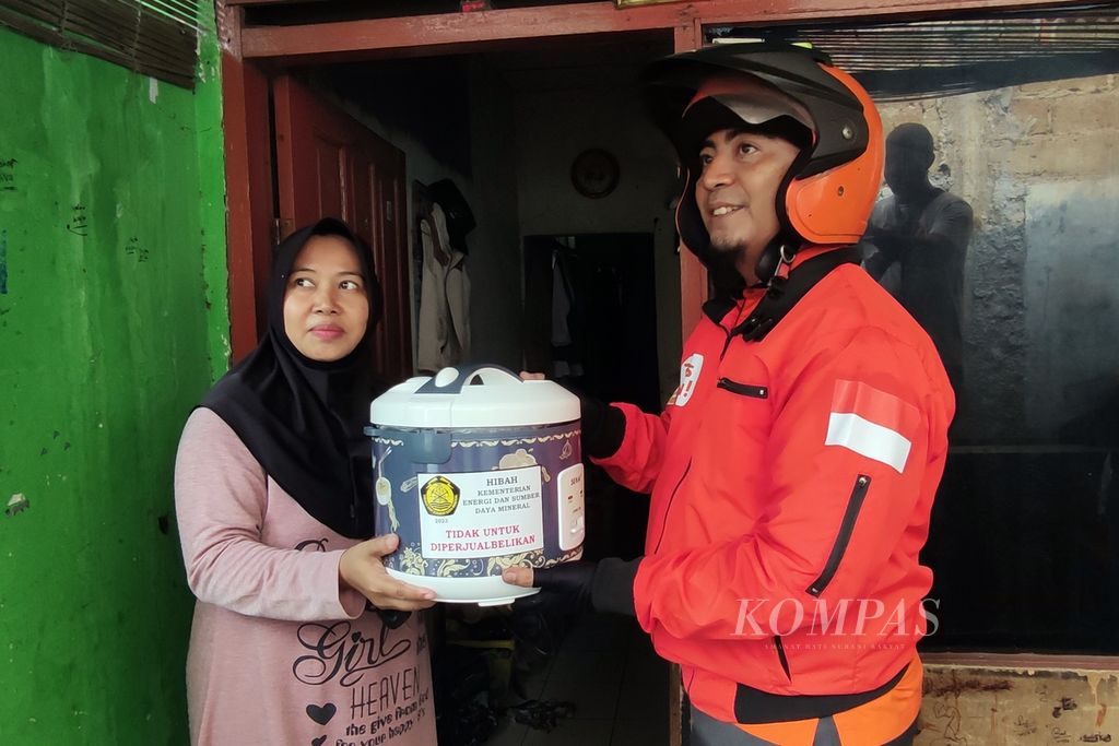 Petugas salur PT Pos Indonesia menyerahkan alat memasak berbasis listrik, yakni <i>rice cooker</i>, dari Kementerian Energi dan Sumber Daya Mineral, Selasa (12/12/2023). 
