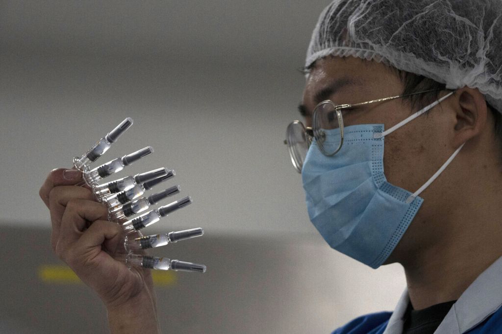 An employee manually inspects syringes of the SARS CoV-2 Vaccine for COVID-19 produced by SinoVac at its factory in Beijing on Thursday, Sept. 24, 2020. A Chinese health official said Friday, Sept. 25,2020, that the country’s annual production capacity for coronavirus vaccines will top 1 billion doses next year, following an aggressive government support program for construction of new factories. 