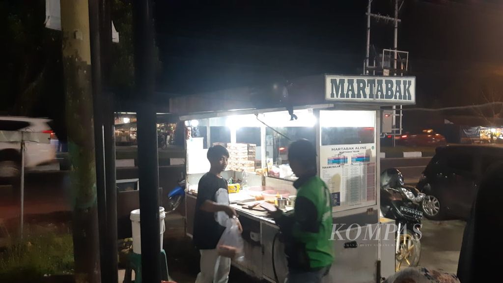 Agus (23) is serving a customer who is buying martabak in Palangka Raya city, Central Kalimantan, on Thursday (18/4/2024). He has only been living in Palangka Raya for a month in search of a living, away from his hometown in Central Java.