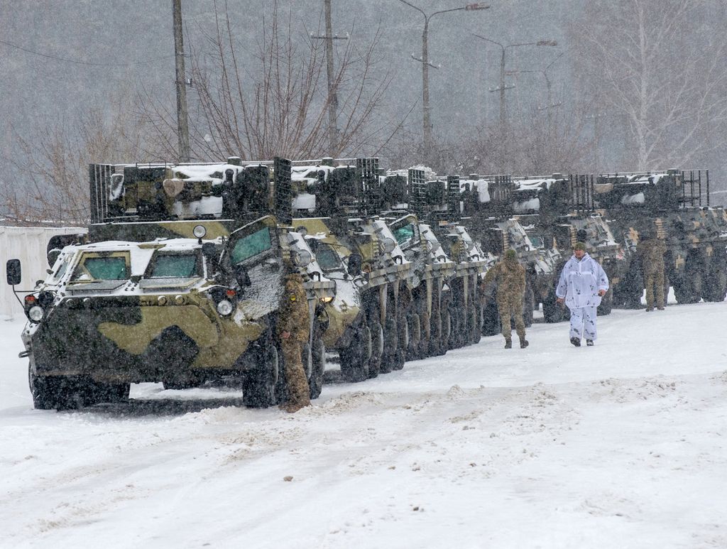 Beberapa anggota militer Ukraina berjalan di samping kendaraan tempur dari Batalion 92 di Klugino-Bashkirivka, di dekat wilayah Kharkiv, Senin (31/1/2022).