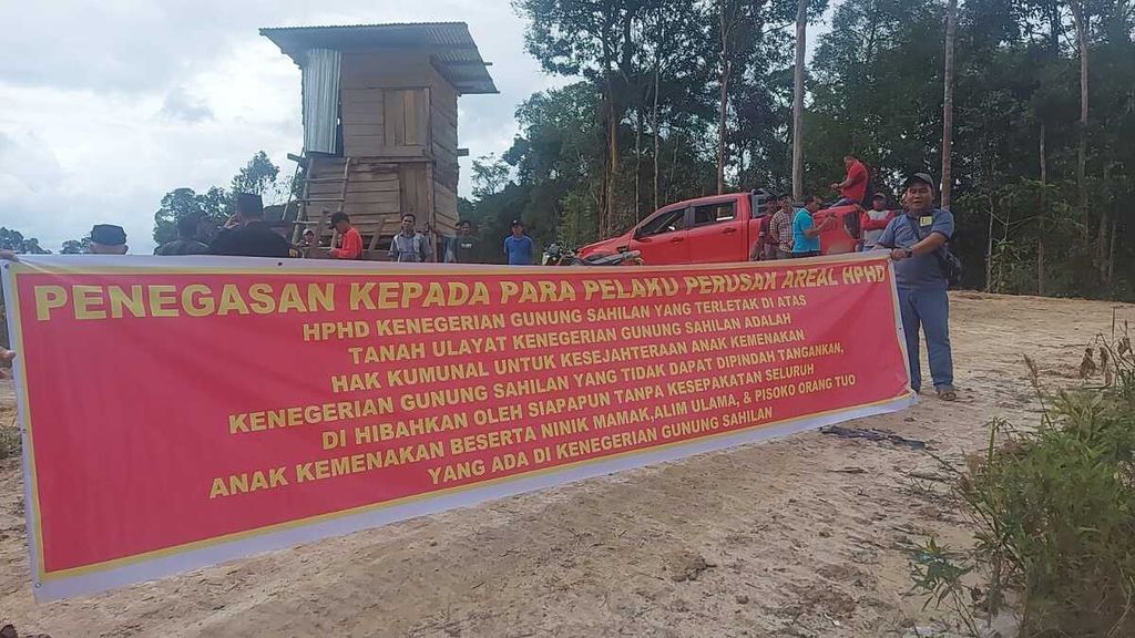 Warga membentangkan spanduk di hutan desa di Kenegerian Gunung Sahilan, Kecamatan Gunung Sahilan, Kampar, Riau, yang mengalami perambahan, Sabtu (4/3/2023). Hutan desa ini merupakan hutan penyangga Taman Nasional Tesso Nilo.