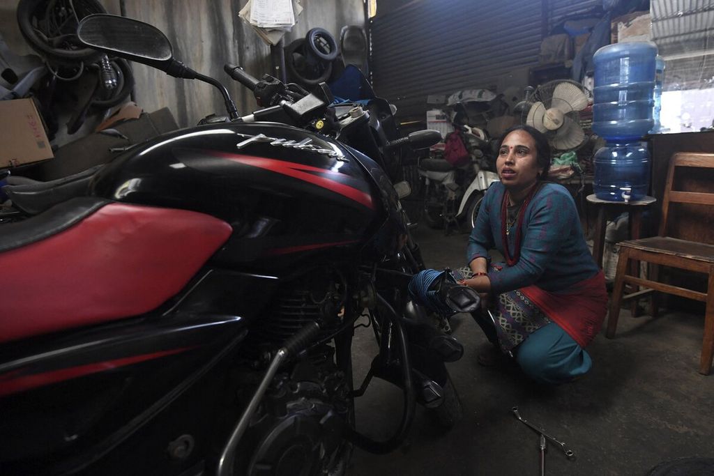 Seorang mekanik perempuan memperbaiki sepeda motor di bengkelnya di Lalitpur, pinggiran Kathmandu, Nepal, Senin (7/3/2022). 