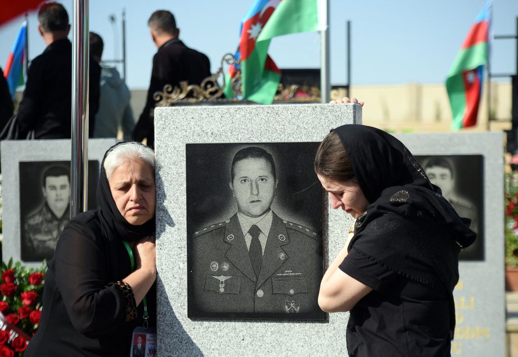Residents mourn at a cemetery in Baku, Azerbaijan, on Wednesday (27/9/2023), near a photo of Azerbaijani soldiers who died in the second Karabakh war. Azerbaijan commemorates the third anniversary of the outbreak of the 44-day war, which began on September 27, 2020.