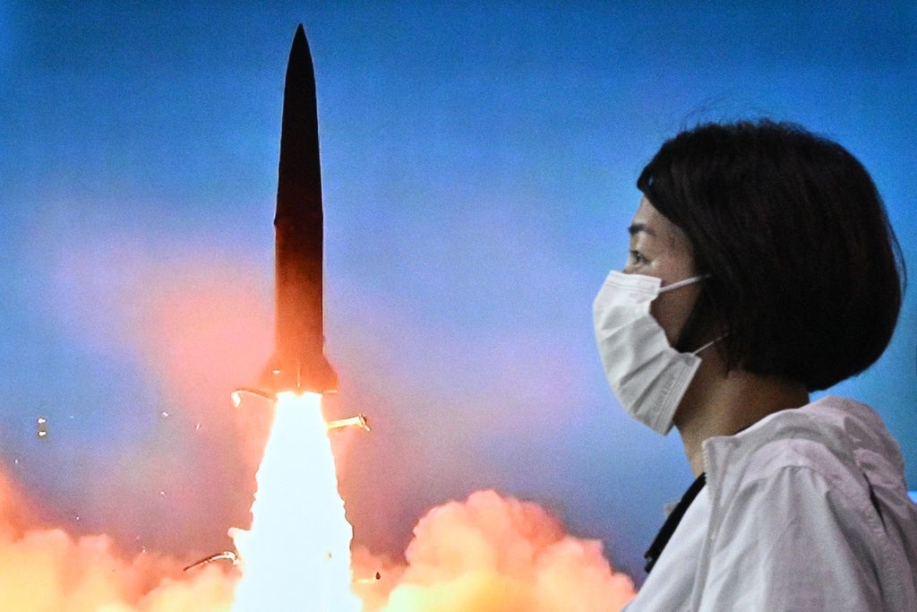 Seorang perempuan berjalan melewati layar yang menayangkan siaran cuplikan uji coba rudal Korea Utara di sebuah stasiun kereta di Seoul, 5 Juni 2022. 