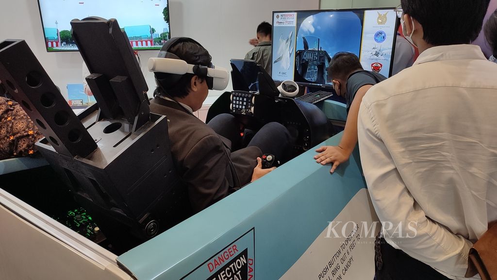Pengunjung manjajal simulator F-16 yang berada di stan TNi Angkatan Udara di ajang Indo Defence 2022, Sabtu (5/11/2022), di Jiexpo Kemayoran, Jakarta.