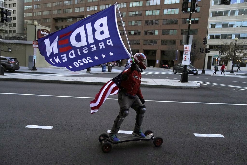 Pendukung Joe Biden menggunakan skateboard sambil membawa bendera berkeliling di jalanan menjelang upacara pelantikan Presiden terpilih Joe Biden dan Wakil Presiden terpilih Kamala Harris, di Washington, AS, Senin (18/1/2021). Inflasi menjadi tantangan terbesar bagi ekonomi domestik AS. 