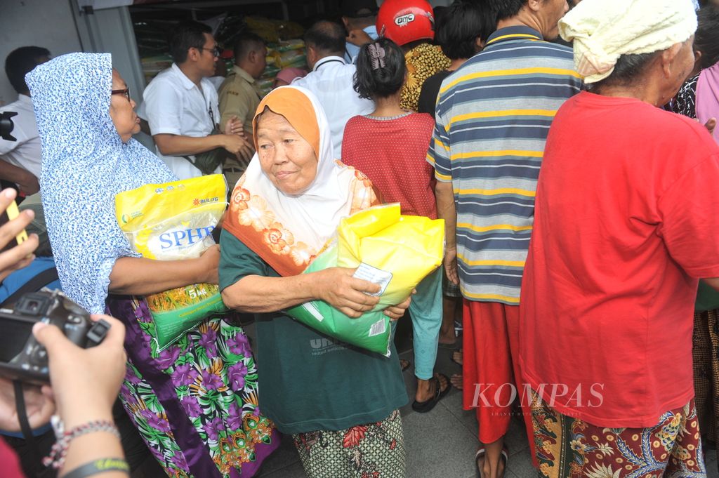 Warga membawa beras pemberian dari Menteri Perdagangan Zulkifli Hasan saat sidak di kios Tim Pengendali Inflasi Daerah Kota Surabaya di Pasar Genteng Baru, Surabaya, Senin (4/12/2023). 