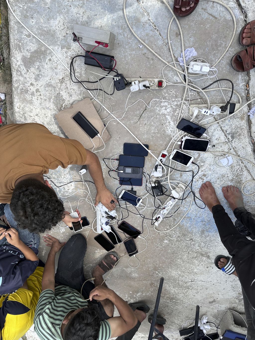 Dalam foto yang disediakan UNRWA ini, warga yang mengungsi mengisi daya perangkat seluler mereka di tempat penampungan di Gaza selatan pada Senin (16/10/2023). 
