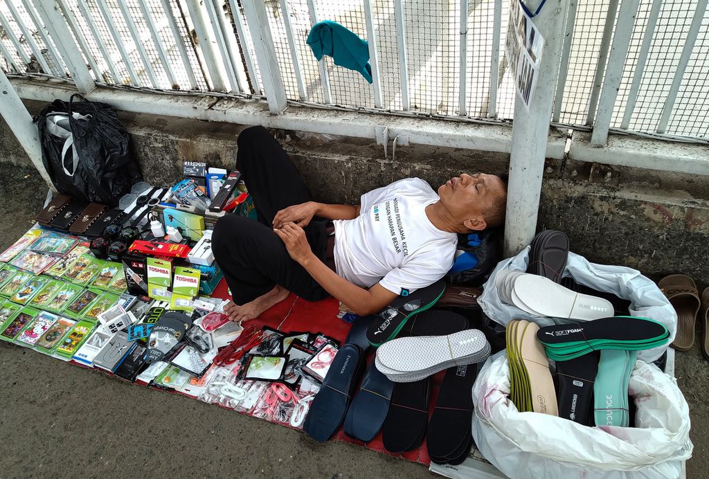 Pedagang kaki lima terlelap saat menunggu pembeli di atas jembatan penyeberangan orang di kawasan Pancoran, Jakarta Selatan.