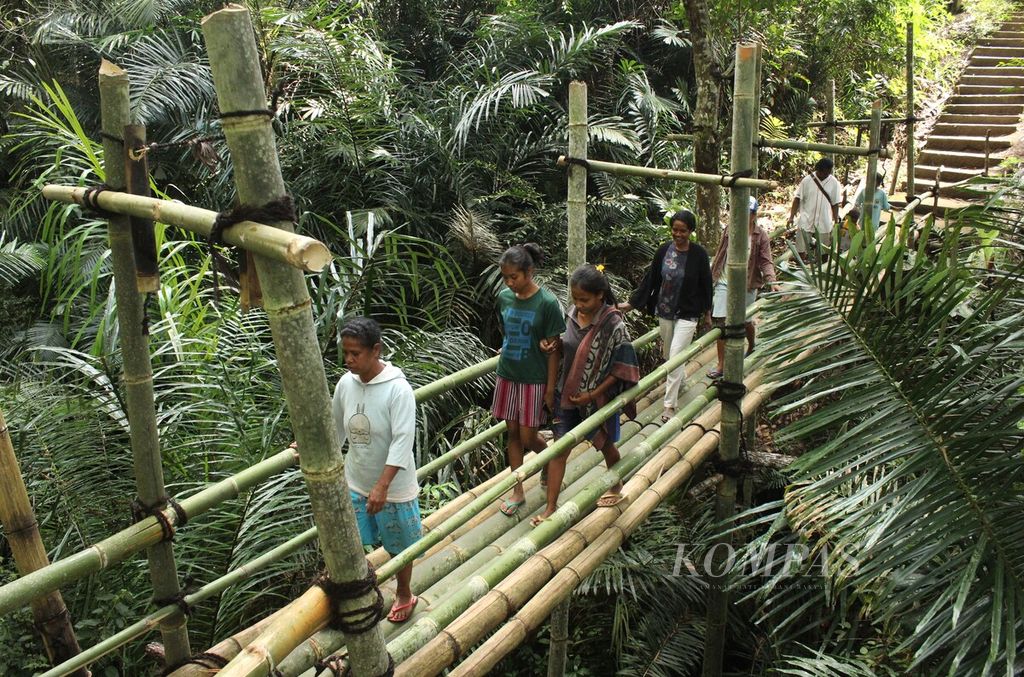 Warga melintasi jembatan bambu di Desa Wolowea, Kabupaten Nagekeo, Nusa Tenggara Timur, Rabu (22/6/2022).