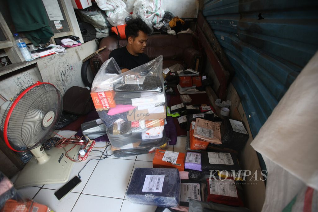 Rio (23), kurir ekspedisi, memilih barang yang akan diantarnya di titik pengedropan logistik barang dari gudang di Cipinang Jaya, Jakarta, 6 April 2022. 