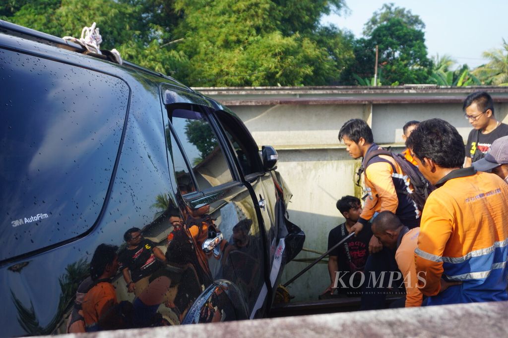 Petugas berusaha mengevakuasi mobil yang masuk rel dan terjepit di jembatan di Sumpiuh, Banyumas, Jawa Tengah, Rabu (19/4/2023) pagi.