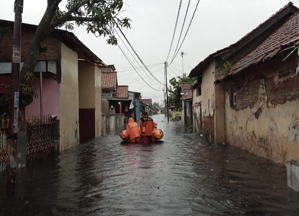 Petugas BPBD Kota Pekalongan, Jawa Tengah, membawa perahu karet untuk mengevakuasi warga yang terjebak banjir, Sabtu (31/12/2022). 