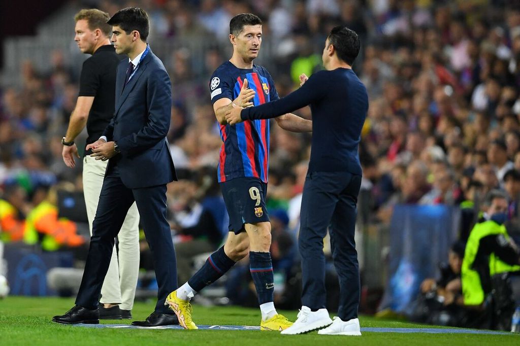 Pelatih Barcelona Xavi (kanan) menyambut Robert Lewandowski yang ditarik ke bangku cadangan saat melawan Bayern Muenchen pada laga Liga Champions di Stadion Spotify Camp Nou, Barcelona, Rabu (26/10/2022). Pada laga itu, Barcelona kalah 0-3. 