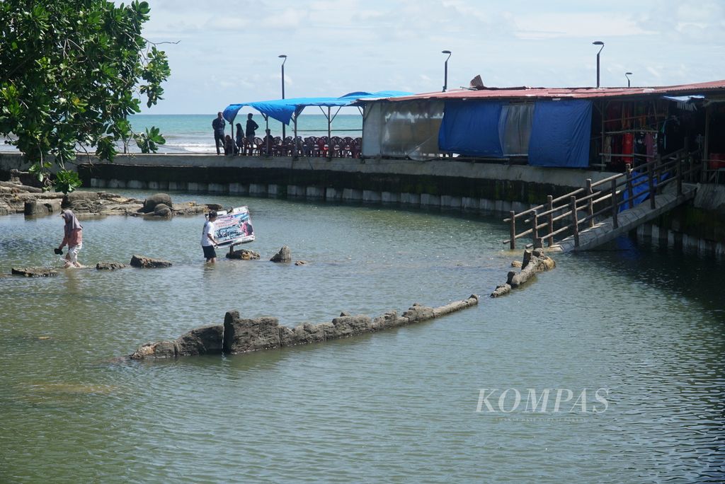 Wisatawan mengamati obyek wisata batu Malin Kundang yang tenggelam akibat hujan di kawasan Pantai Air Manis, Kota Padang, Sumatera Barat, Senin (28/8/2023). 