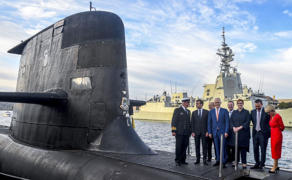 Dalam foto tanggal 2 Mei 2018 ini, terlihat Presiden Perancis Emmanuel Macron (kedua dari kanan) dan Perdana Menteri Australia Malcolm Turnbull (tengah) berdiri di atas kapal selam kelas Collins, HMAS Waller, yang dioperasikan Angkatan Laut Australia di Garden Island, Sydney, Australia. 
