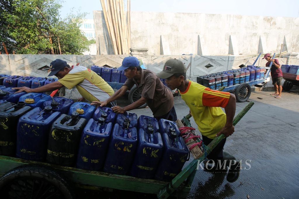 Pedagang air pikulan keliling mengisi jeriken di agen air di Muara Angke, Penjaringan, Jakarta Utara, Kamis (22/8/2019). Saat musim kemarau, permintaan air pikulan bisa meningkat hingga dua kali lipat daripada saat musim hujan.