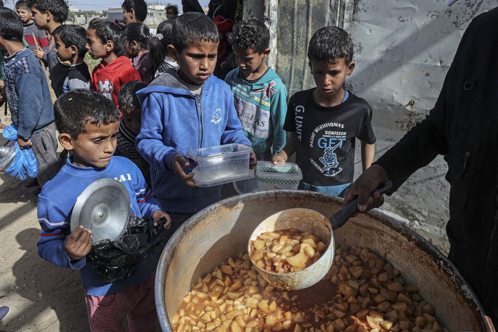 Anak-anak Palestina menerima jatah buka puasa gratis selama bulan suci Ramadhan di Rafah di Jalur Gaza selatan, Senin (4/4/2022).