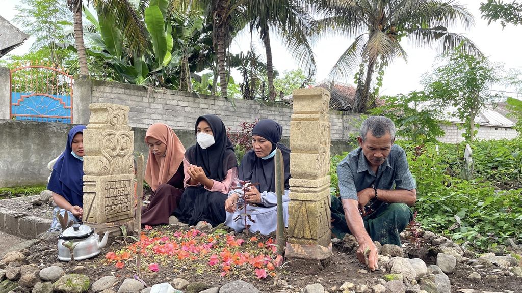 Supriani  (second from right) with family members visits the grave of his daughter-in-law Julia Ningsih (19), at the Dasan Borok Village Public Cemetery, Suralaga District, East Lombok Regency, West Nusa Tenggara, Friday (21/1/2022). Julia Ningsih, who left for Malaysia with Junaidi, her husband, was one of the victims who died in a non-procedural Indonesian Migrant Worker ship accident in the waters of Johor, Malaysia, in mid-December 2021.