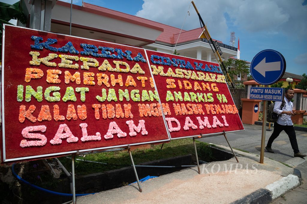 Warga melintas di depan papan bunga berisi imbauan ancaman penjara bagi warga yang anarkistis di Pengadilan Negeri Batam, Kepulauan Riau, Senin (6/11/2023).