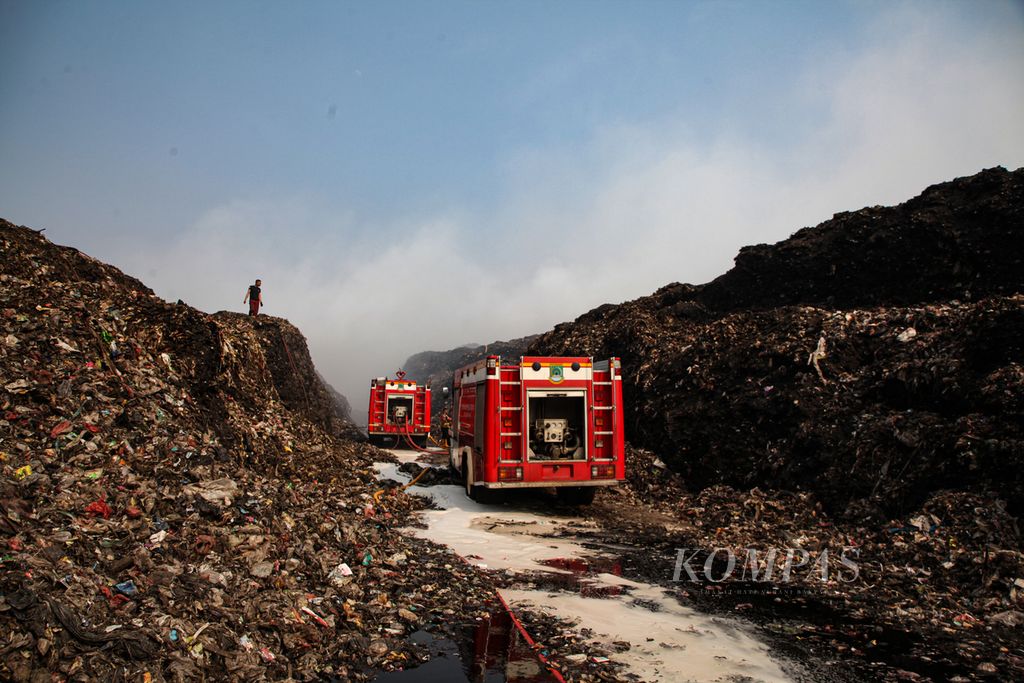 Dua mobil pemadam kebakaran menembus hingga ke area tengah gunungan sampah untuk memadamkan kebakaran di Tempat Pemrosesan Akhir (TPA) Rawa Kucing, Senin (23/10/2023). 