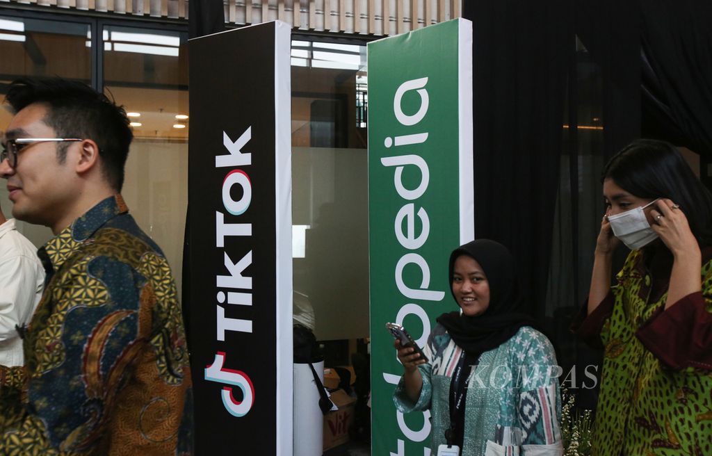 Tamu undangan melintas di dekorasi tulisan Tokopedia dan Tiktok saat peluncuran kampanye Beli Lokal pada Hari Belanja Nasional atau Harbolnas 12.12, di kantor Tokopedia, Jakarta, Selasa (12/12/2023). Tokopedia berkolaborasi dengan Tiktok Indonesia pada Harbolnas 12.12 melalui kampanye Beli Lokal.