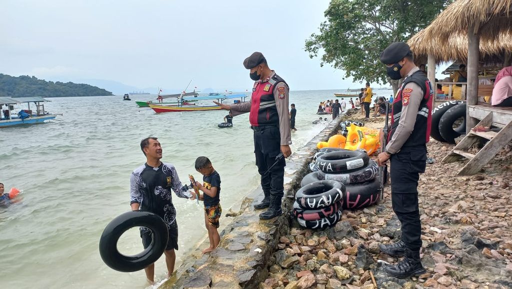 Anggota polisi dari Polres Pesawaran berpatroli ke Pantai Mutun yang menjadi salah satu objek wisata favorit di Kabupaten Pesawaran, Lampung, pada Senin (26/12/2022). Wisatawan diimbau untuk berhati-hati saat bermain di laut karena saat ini gelombang laut cukup tinggi.