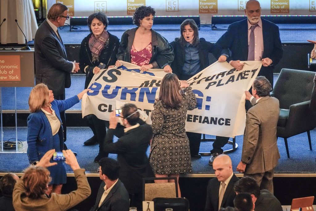 Hadirin mencoba mengambil poster dari para aktivis iklim yang memprotes di panggung sebelum Gubernur Bank Sentral AS Jerome Powell berbicara di Economic Club of New York, 19 Oktober 2023, di New York, Amerika Serikat. 
