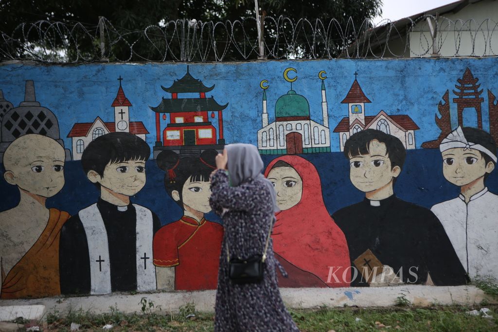 Warga melintasi mural kerukunan beragama di Pekayon, Kota Bekasi, Jawa Barat, Rabu (2/8/2023). Toleransi dan persatuan bangsa menjadi edukasi meningkatkan rasa nasionalisme generasi muda.