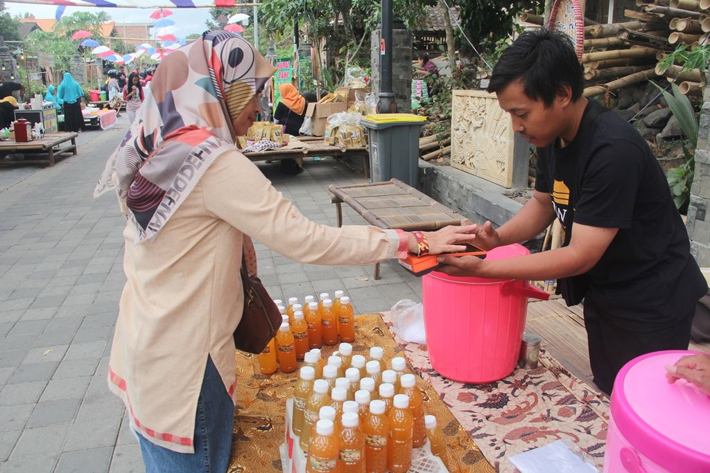 Pengunjung menggunakan Gelang Duit Kampung sebagai alat pembayaran saat membeli produk kuliner dalam Festival Sinergi dan Harmoni, Sabtu (2/11/2019), di kawasan Candi Pawon, Desa Wanurejo, Kecamatan Borobudur, Kabupaten Magelang, Jawa Tengah.