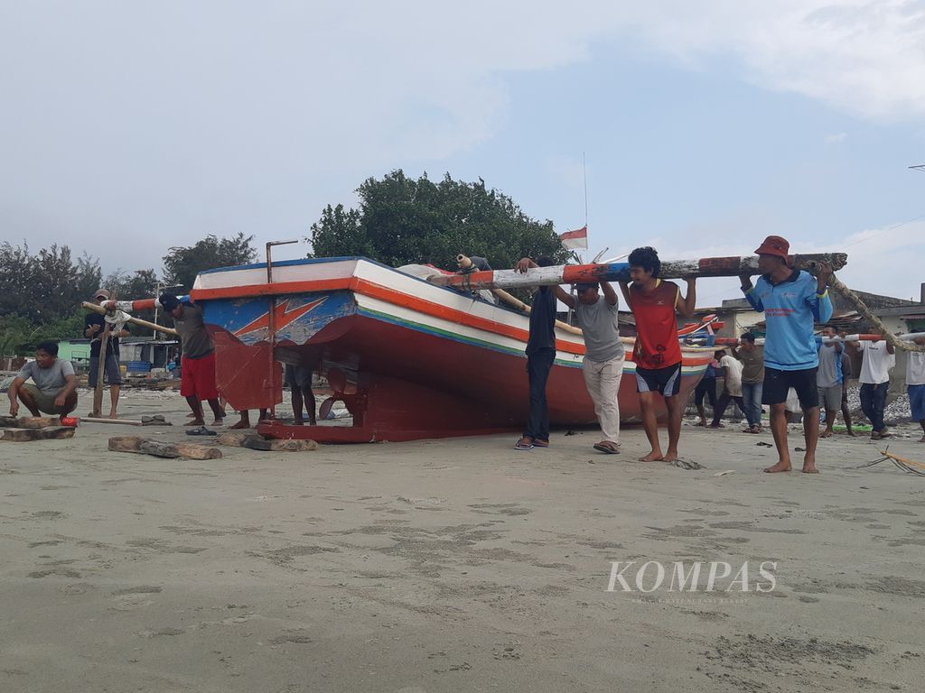 Nelayan yang bermukim di kampung nelayan tradisional Malabero, Kota Bengkulu, bergotong royong mendorong kapal yang hendak digunakan untuk melaut pada Rabu (15/11/2023) sore. 