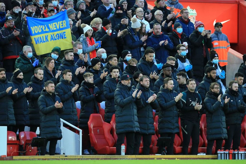 Manajer Liverpool Juergen Klopp (tengah) dan anggota staf Liverpool bertepuk tangan sambil berdiri sebagai bentuk dukungan terhadap Ukraina sebelum pertandingan Liga Inggris antara Liverpool dan West Ham United di Stadion Anfield, Liverpool, Sabtu (5/3/2022).