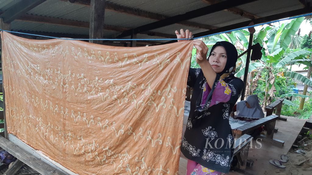 Sulastri (38), perajin batik tulis, sedang menjemur kain batik yang diwarnai dengan pewarna alami dari kulit jengkol di rumahnya di Kelurahan Pinang Jaya, Kecamatan Kemiling, Bandar Lampung, Selasa (15/3/2022).